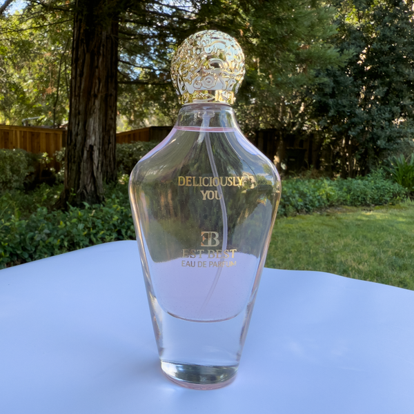DELICIOUSLY YOU perfume bottle with cap displayed in outdoor natural sunlight.