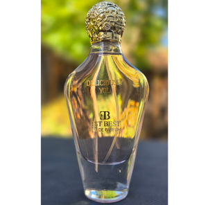 DELICIOUSLY YOU perfume bottle glowing against warm yellow bokeh background.